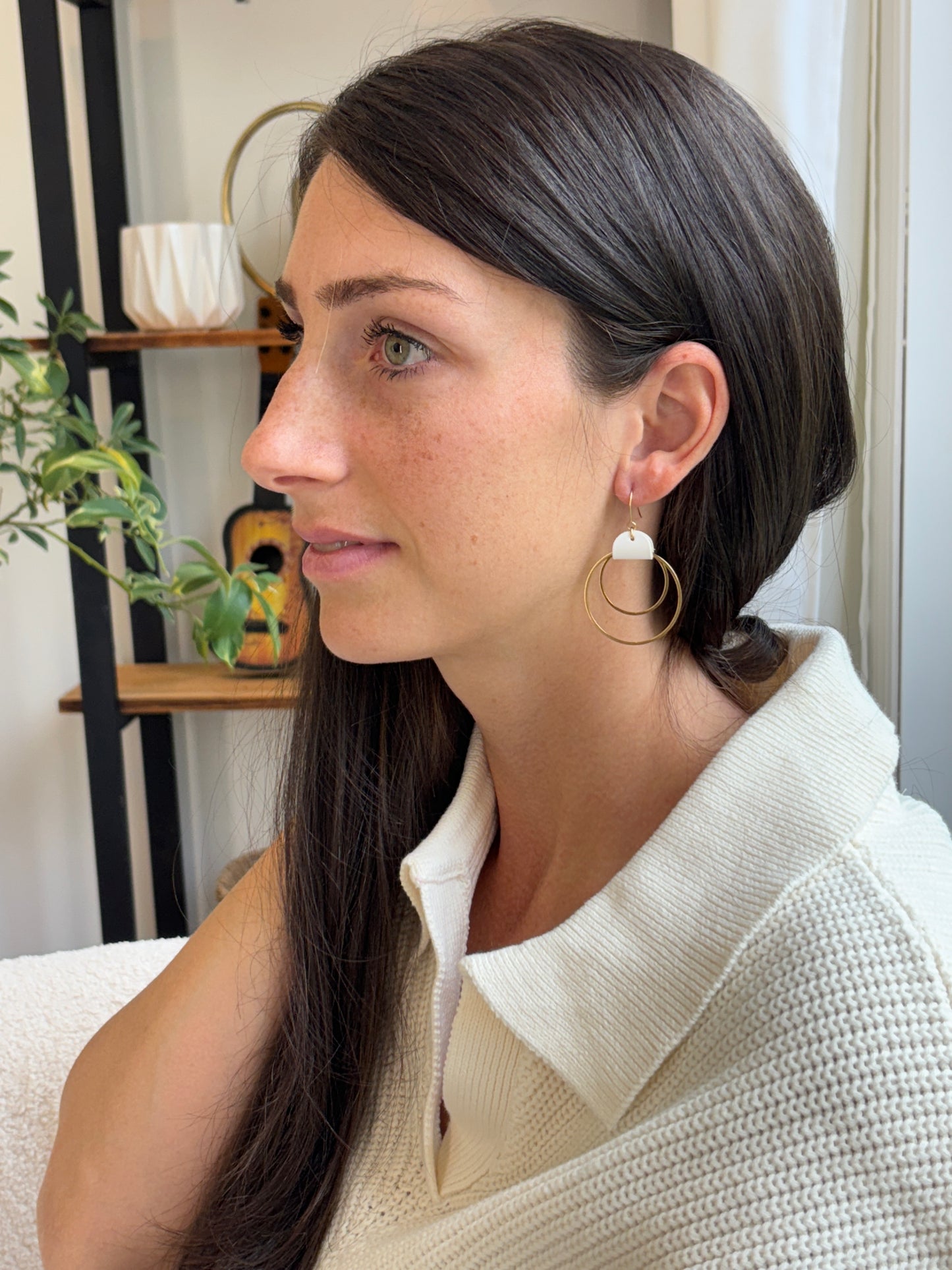 Woman wearing gold hoop earrings in a minimal indoor setting