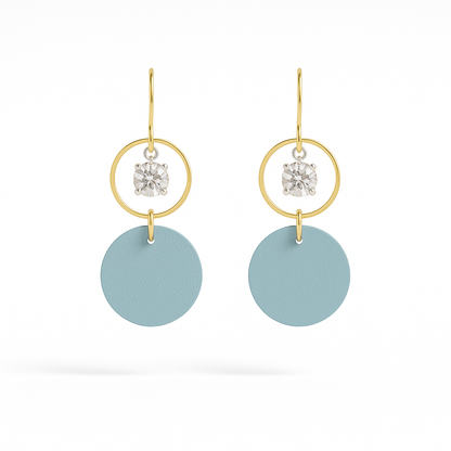 A pair of blue leather statement earrings featuring gold-plated rings and crystal details on a white background.
