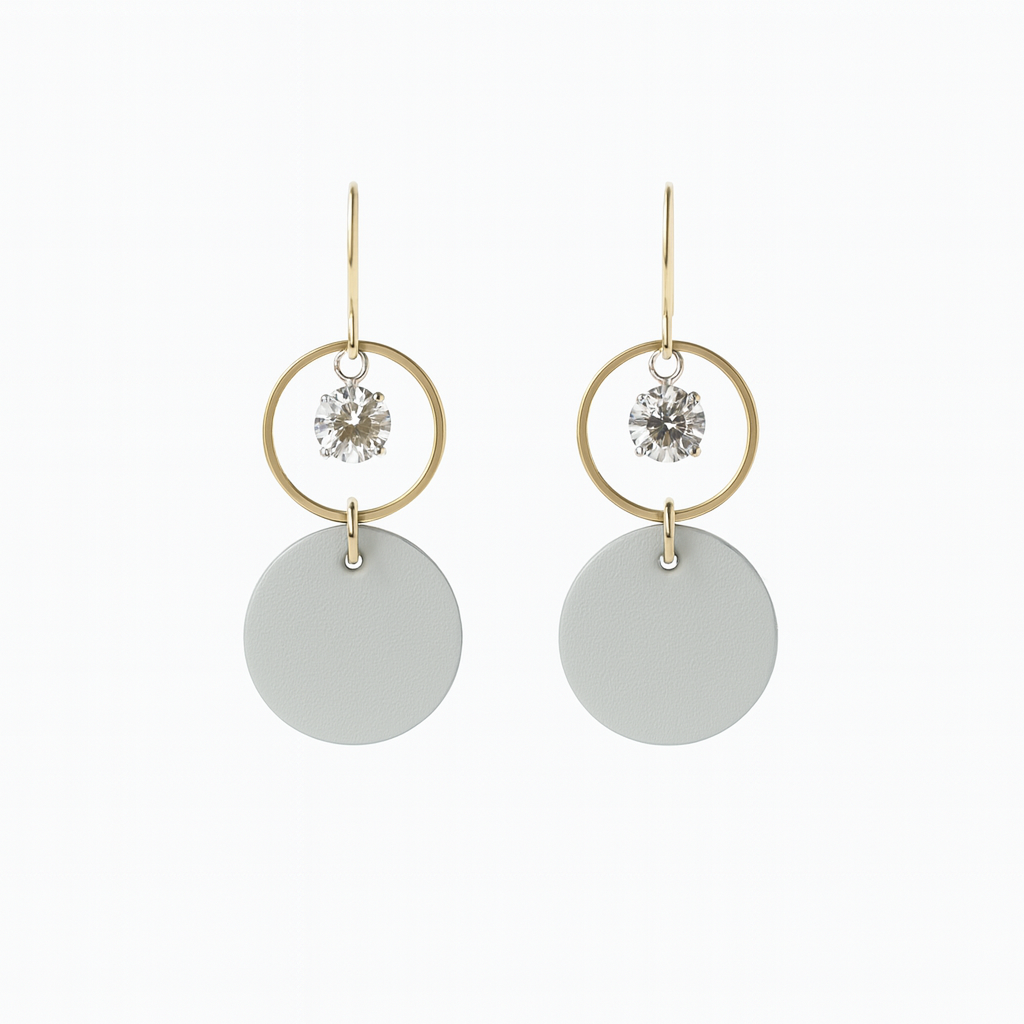 Pair of light gray leather statement earrings featuring gold-plated rings and crystal details on a white background.
