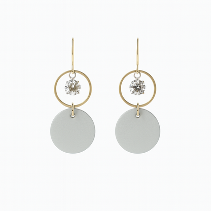 Pair of light gray leather statement earrings featuring gold-plated rings and crystal details on a white background.