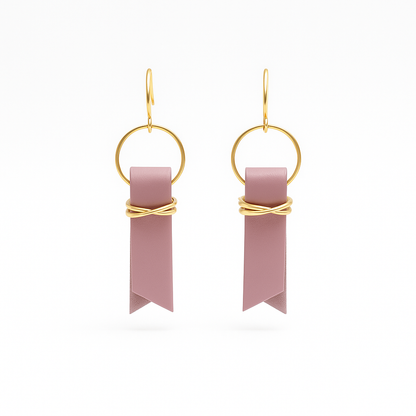A pair of mauve leather ribbon earrings accented with gold-plated wire and rings on a white background.