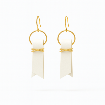 Off-white leather ribbon earrings accented with gold-plated wire and rings on a white background.