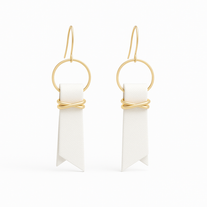 A pair of white leather ribbon earrings accented with gold-plated wire and rings on a white background.